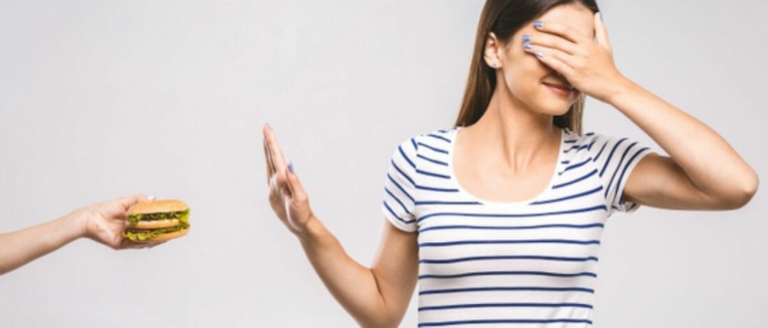 A woman avoiding a burger by closing her eyes