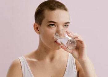 A woman sipping a glass full of water