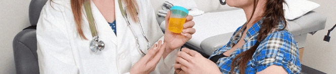 A doctor holding a urine sample while talking to her patient