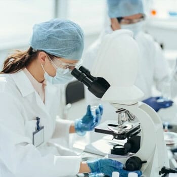 A female medical person in a lab using a microscope