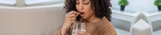 woman drinking a pill and water