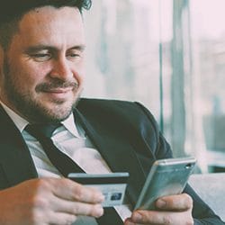 A person holding a credit card and phone
