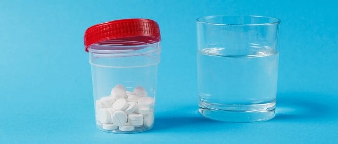A jar of medicine tablets and a glass of water