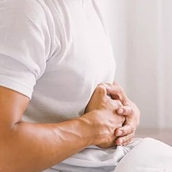 A man metabolizing meth at his bed while holding his stomach