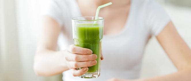 An image of a woman holding a detox drink with a straw