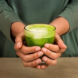 An image of a woman holding a glass of detox drink
