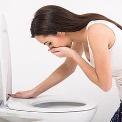 A woman vomiting in the toilet