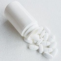 A top view of Zolpidem tablets pouring out of a jar